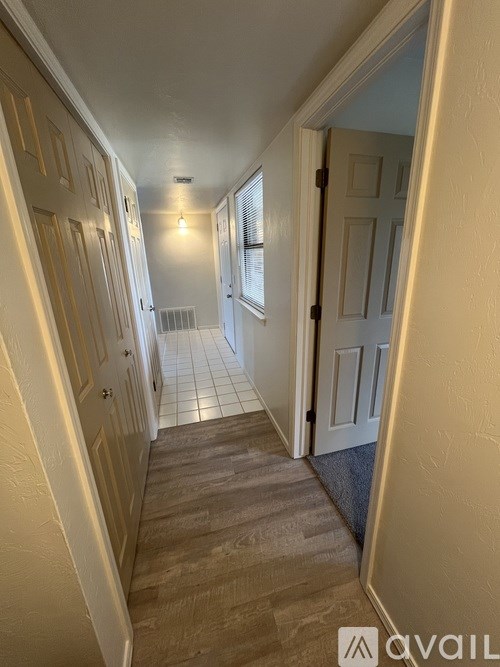 A hallway with wooden floors and white walls.