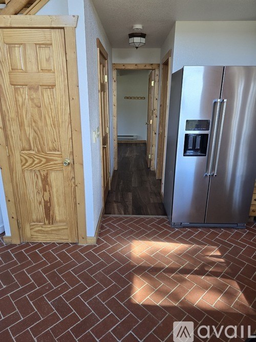 A kitchen with a wooden door and a stainless steel refrigerator.