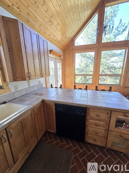 A kitchen with wooden cabinets and a black dishwasher.