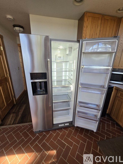 A stainless steel refrigerator with its door open in a kitchen.