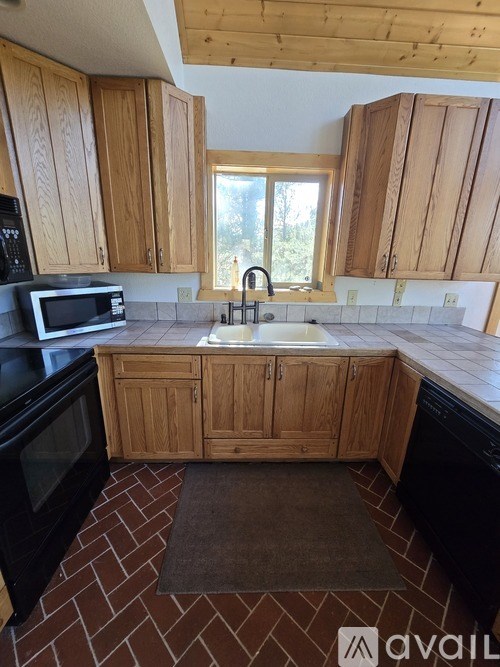 A kitchen with wooden cabinets and a brick floor.