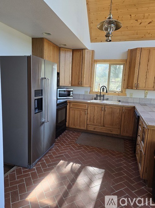A kitchen with wooden cabinets and a brick floor.