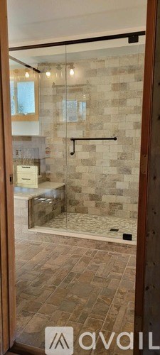 A bathroom with a walk-in shower and a glass door.