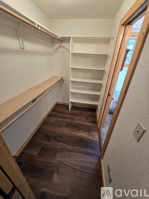A walk-in closet with shelves and a wooden floor.