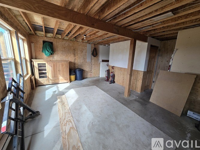 A room under construction with wooden beams on the ceiling and unfinished walls.
