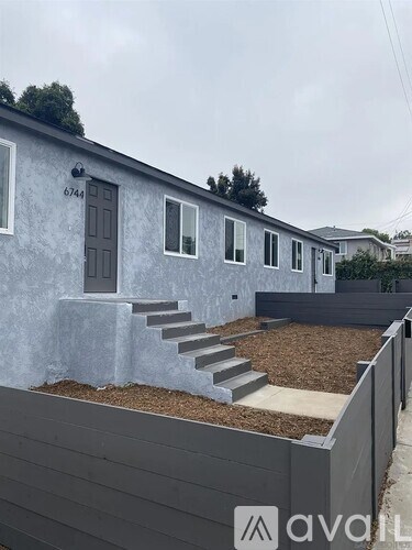 A grey house with a brown door and windows.