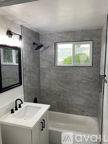 A bathroom with a tub, sink, and window.