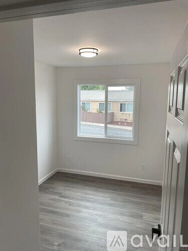 A room with a window and a wooden floor.