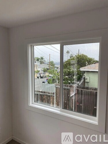 A window with a view of a street and houses outside.