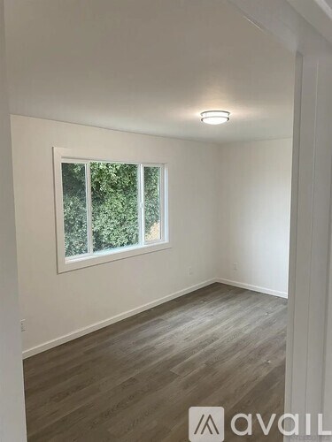 A room with a window and wooden flooring.