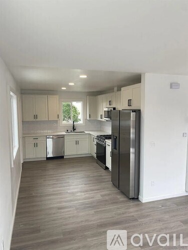 A kitchen with white cabinets and a wooden floor.