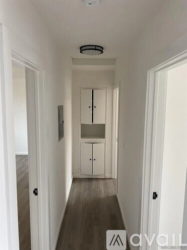 A hallway with a cabinet and a door on the right.