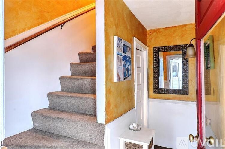 A staircase with a grey carpeted runner and white risers.