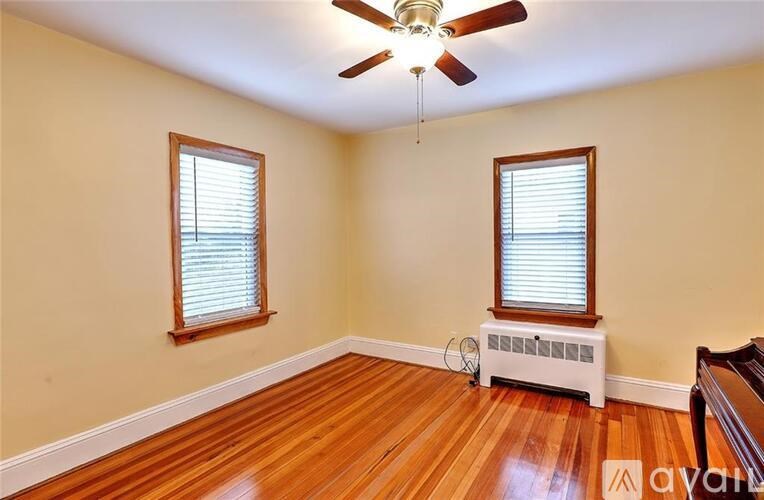 A room with a ceiling fan and a window with blinds.
