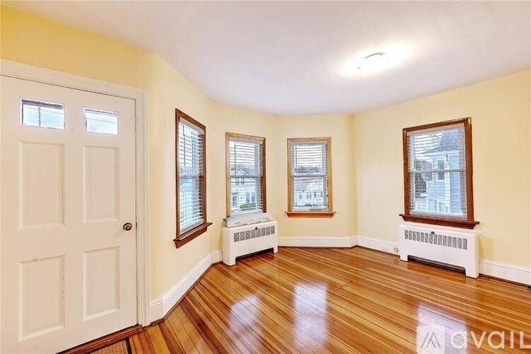 A room with wooden floors and three windows with white frames.