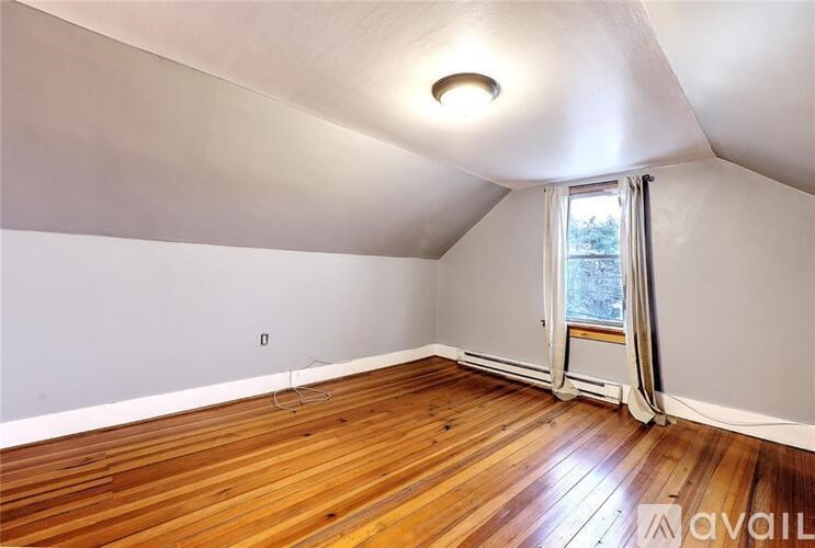 A room with wooden floors and a window with a view of trees outside.