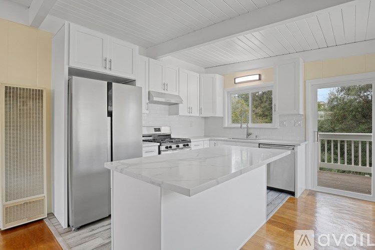 A kitchen with white cabinets and a stainless steel refrigerator.