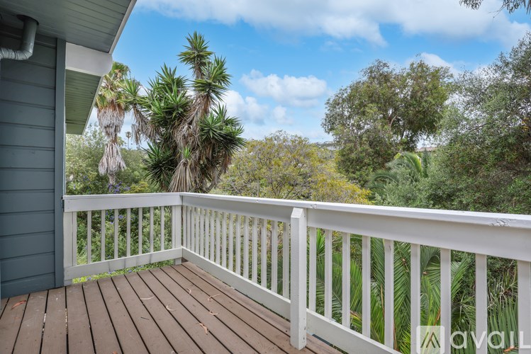 A wooden deck with a white railing overlooks a lush green landscape.