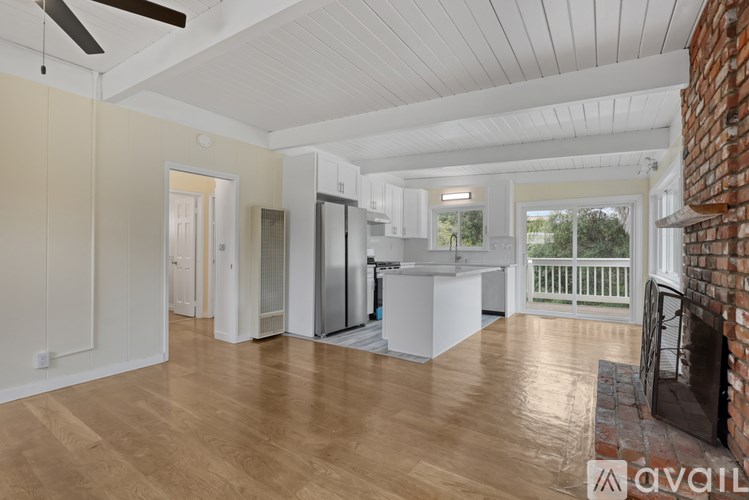 A spacious kitchen with wooden floors and a brick fireplace.