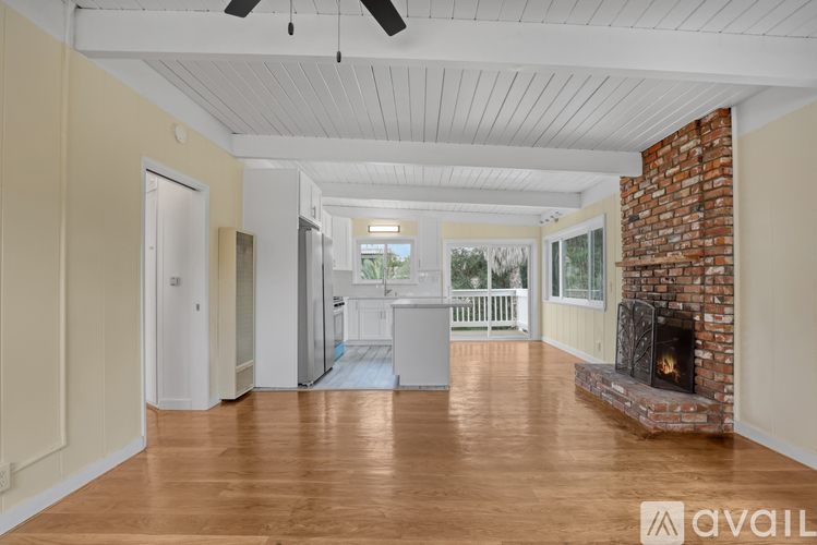 A spacious room with a fireplace and wooden floors.