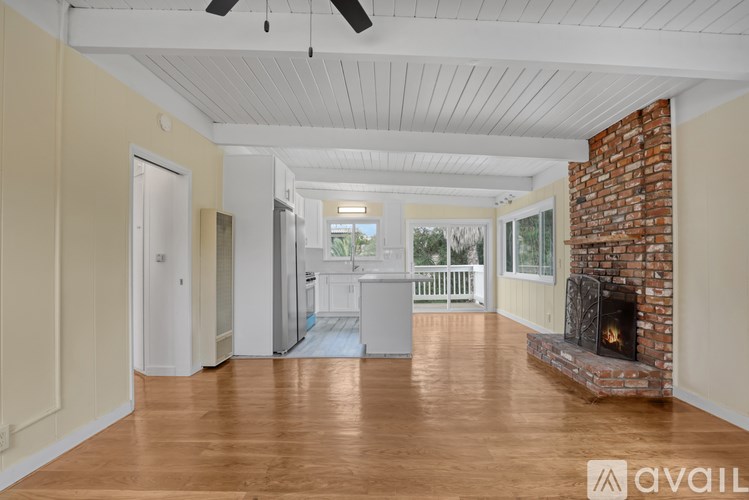 A spacious room with a fireplace and wooden floors.