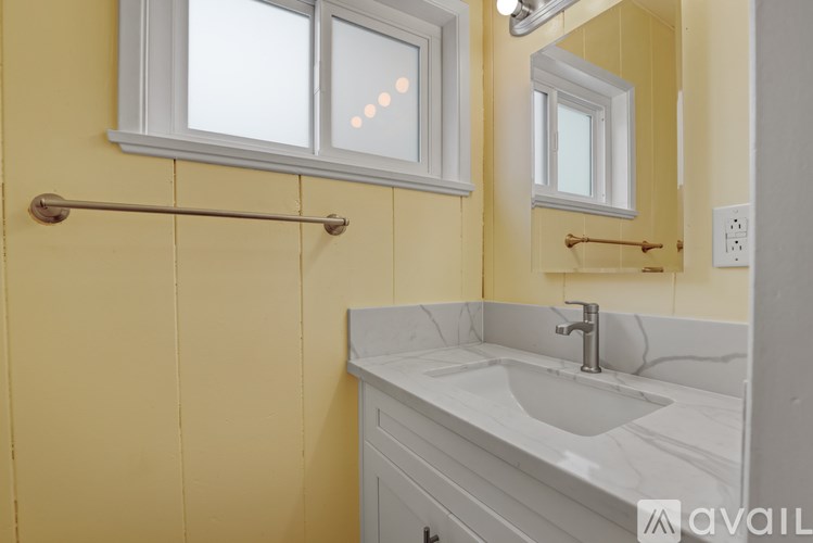 A bathroom with a white sink and a yellow wall.