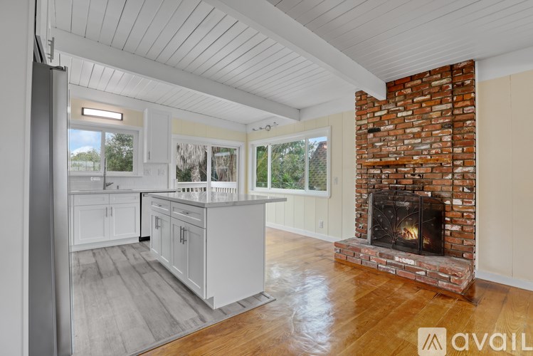 A kitchen with a brick fireplace and wooden floors.