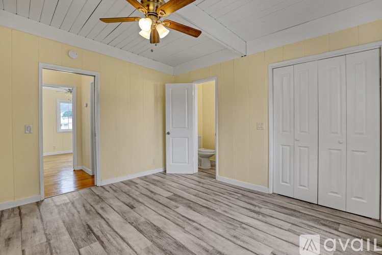 A room with a ceiling fan and wooden flooring.