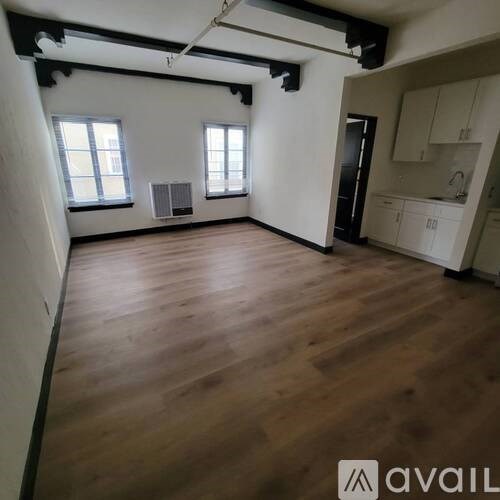 A spacious room with wooden floors and white walls.