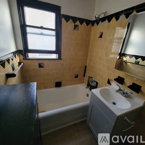 A bathroom with a tub, sink, and window.