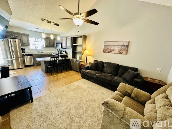 A living room with a black couch and a ceiling fan.