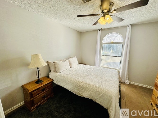 A bedroom with a bed, nightstand, and window.