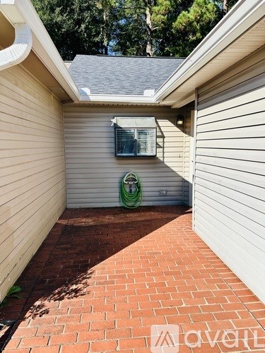 A small patio with a brick border and a hose reel.