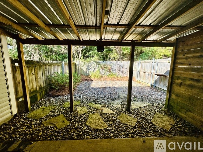 A patio area with a gravel ground and a wooden fence.