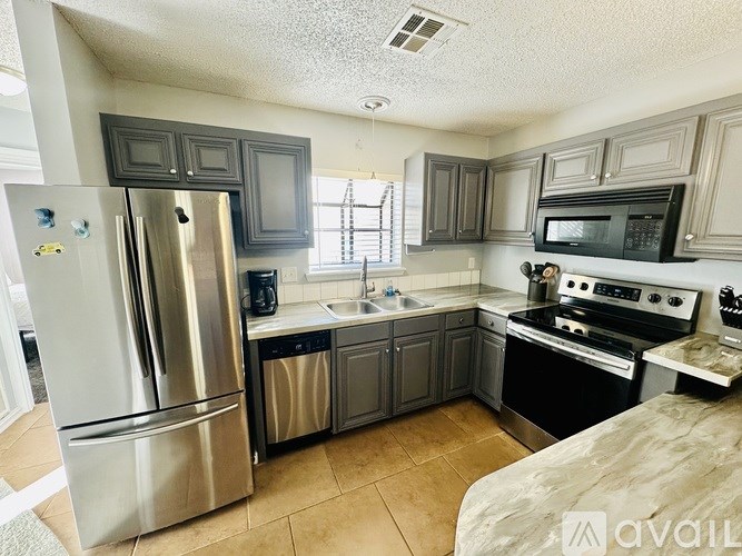A kitchen with a stainless steel refrigerator and a stove top oven.