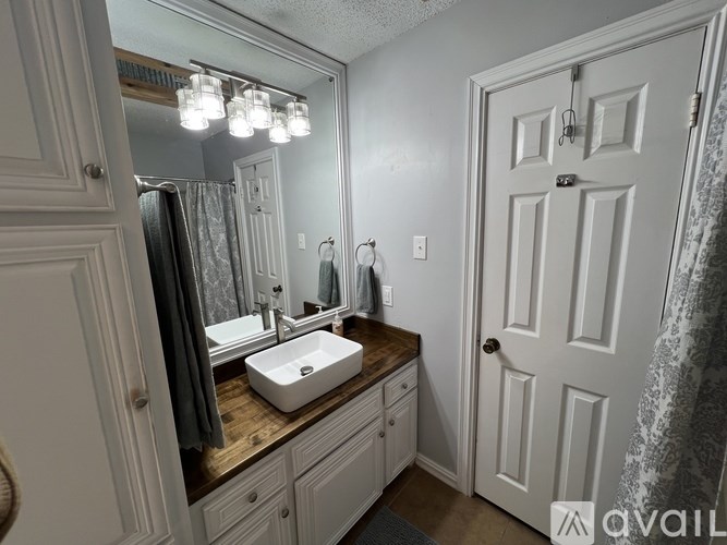 A bathroom with a sink, mirror, and a door.