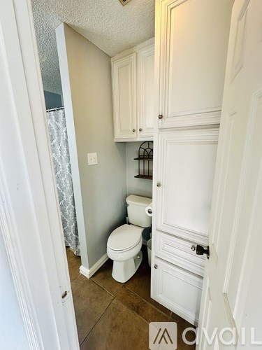 A white toilet in a small bathroom with a cabinet above it.