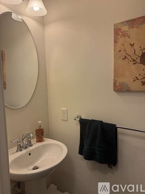 A bathroom with a white sink and a black towel hanging on the rack.