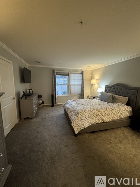 A bedroom with a bed, dresser, and window.