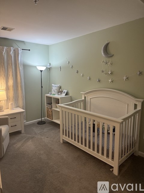 A baby's room with a white crib and a green wall.