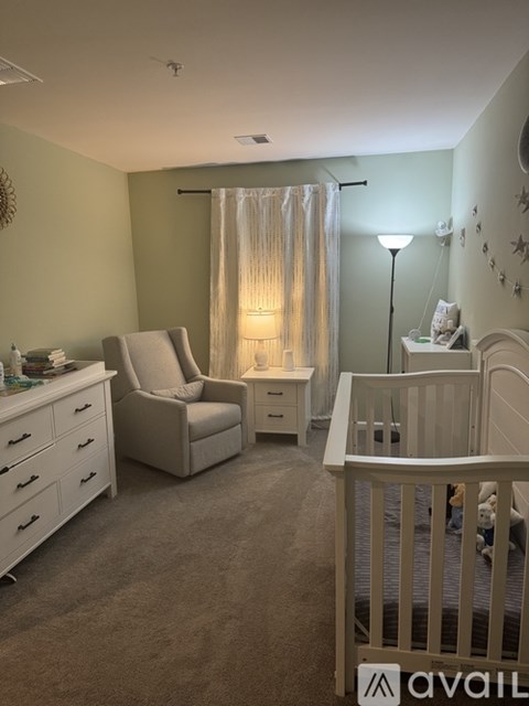 A baby nursery with a crib, chair, and changing table.