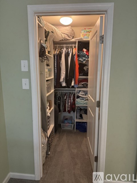 A small closet with clothes hanging and shelves.