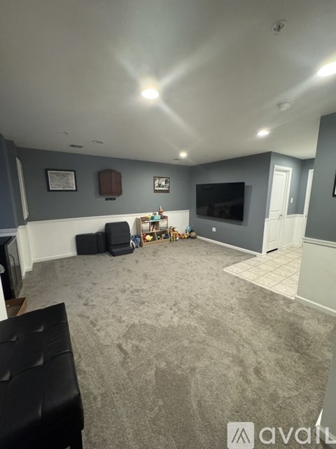 A living room with a grey carpet and a flat screen TV.