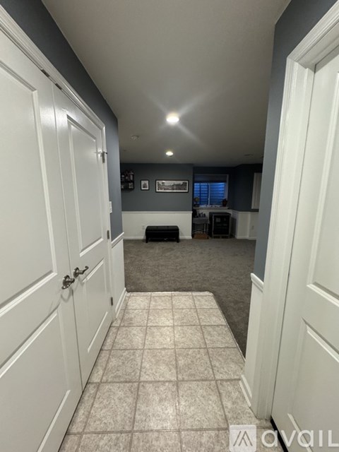 A hallway with white doors and a tiled floor.