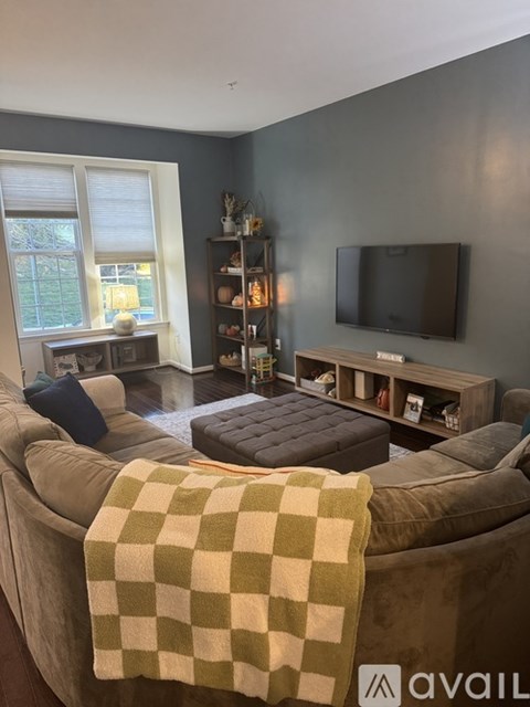 A living room with a couch, a chair, a window, and a television.