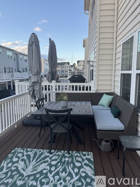 A patio with a table, chairs, and umbrellas.