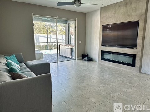 A living room with a grey couch and a television on the wall.