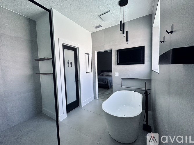 A bathroom with a white tub and a black television.