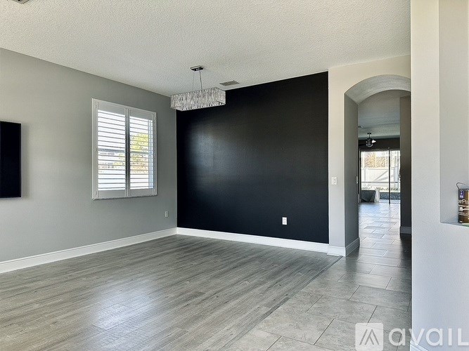 A room with a chandelier and a window with blinds.