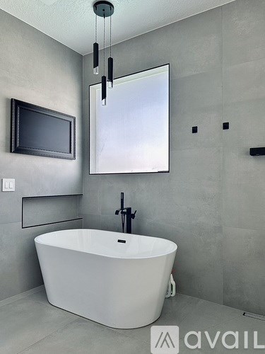 A modern bathroom with a white bathtub and a television mounted on the wall.